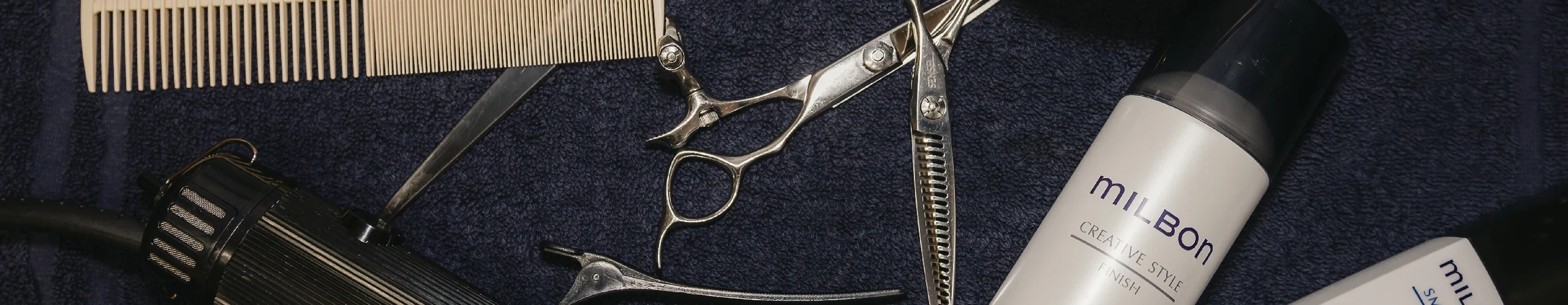 tools for cutting and styling hair laid out on a blue background