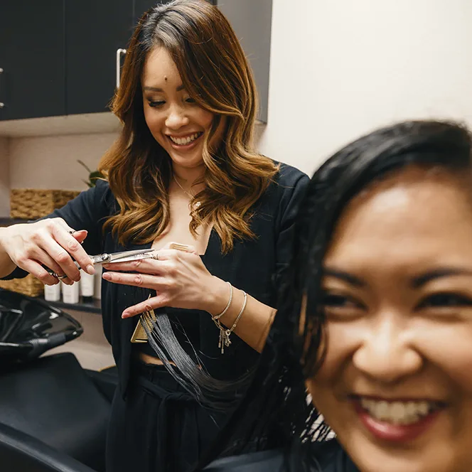 Hair Stylist Amy Soundara trimming ends of female hair